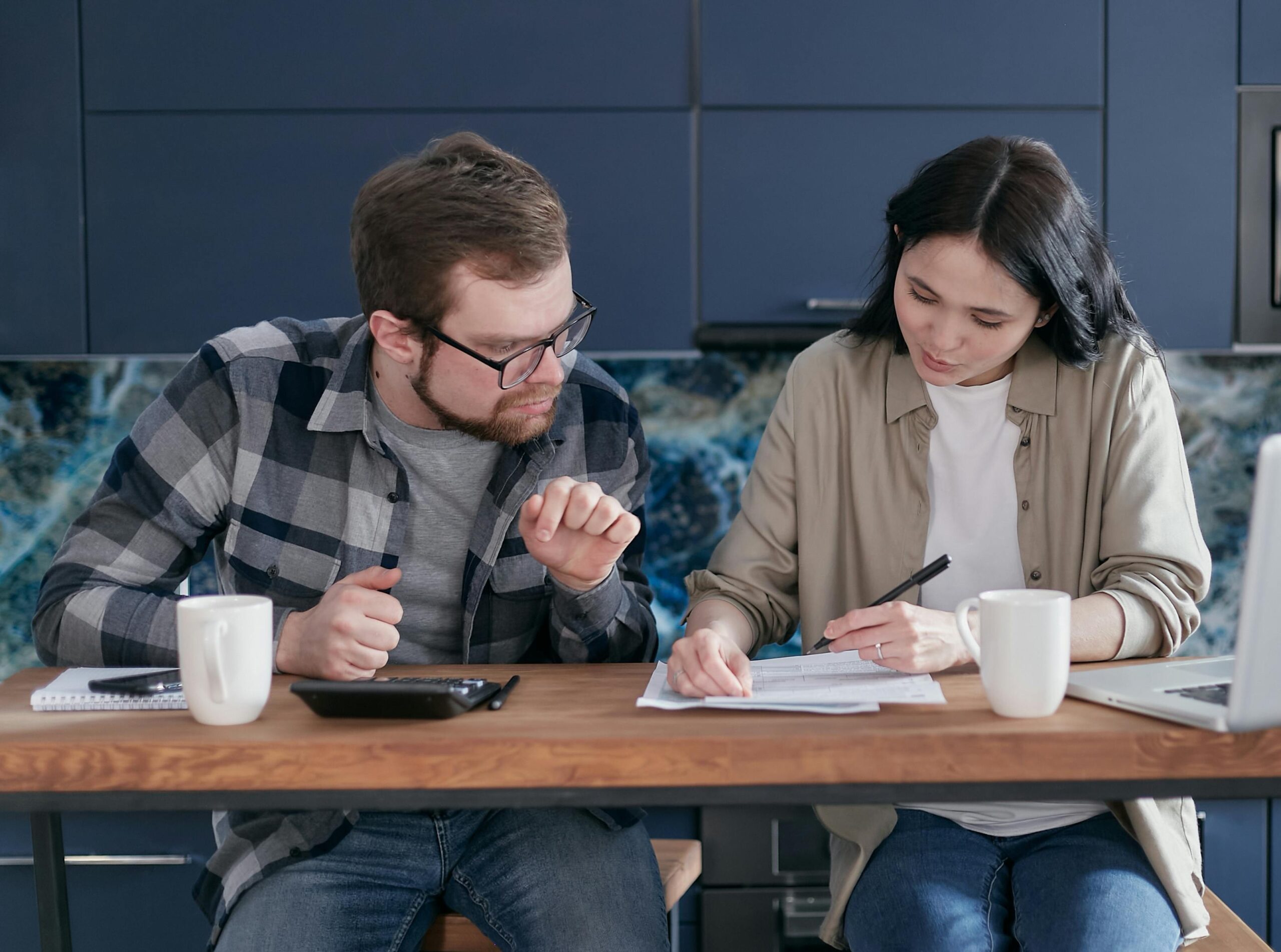 Stressed couple looking at chaotic finances on laptop