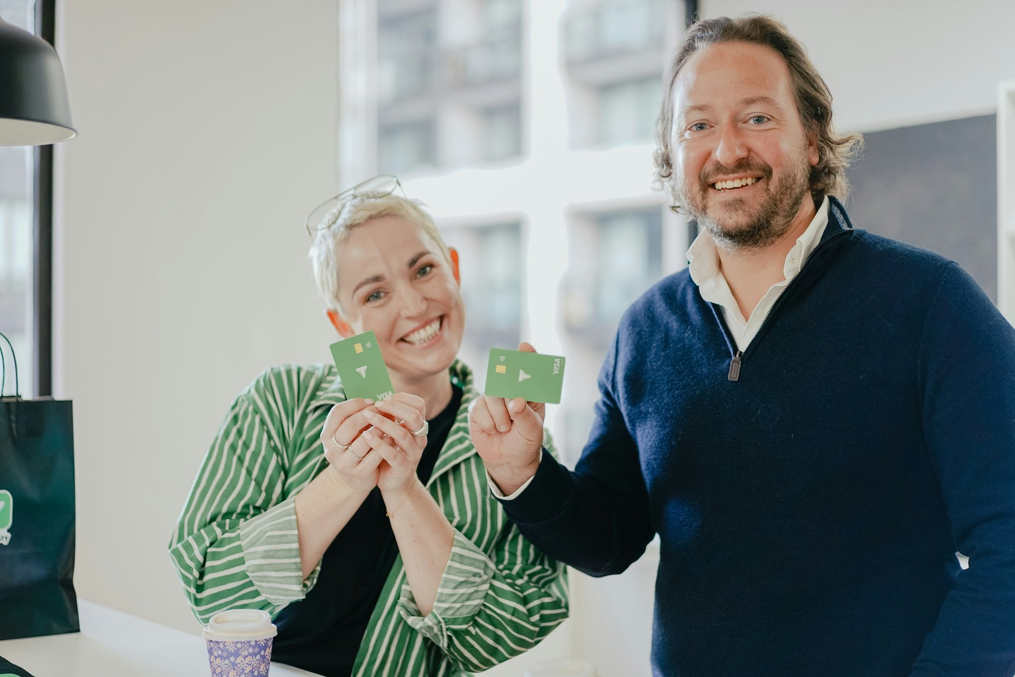 A smiling couple reviewing their joint credit card statement together at a coffee shop.