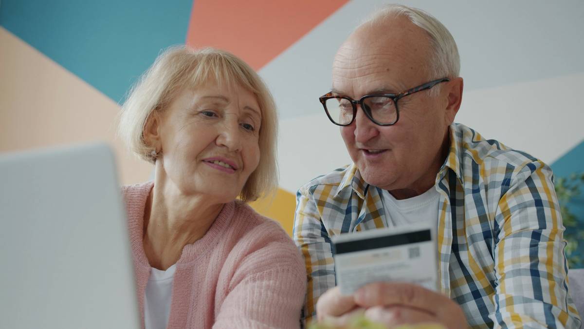 Couple sitting at a table discussing finances with laptops open.