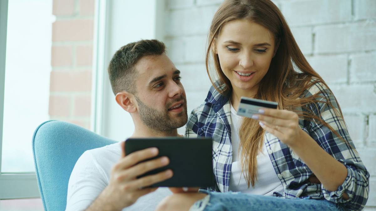 Happy couple swiping joint credit card at restaurant