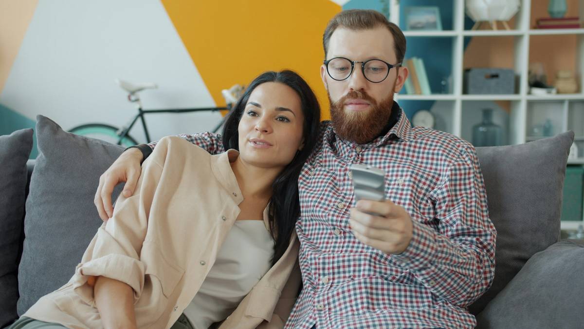 A happy couple reviewing their joint credit card statement at a kitchen table.
